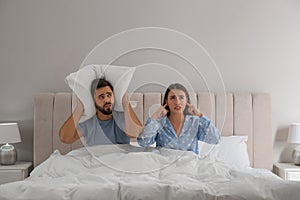 Young couple suffering from noisy neighbours in bed at home