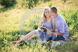 Young couple in the summer on the nature reading a book. The concept of relationships, love and relaxation