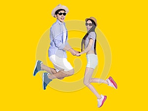 Young couple in sunglasses and  jumping  together .Isolated on yellow background