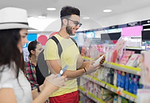 Young Couple In Supermarket Choosing Products Happy Smiling Man And Woman Buying Cosmetics