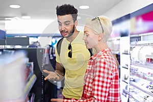 Young Couple In Supermarket Choosing Products Happy Smiling Man And Woman Buying Cosmetics