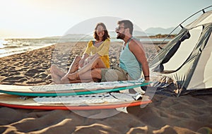 Young couple of surfers is enjoying a beautiful scenery while camping at the beach at sea. Summer, vacation, sea, relationship