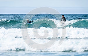 Young couple surfing with surfboard on waves in Atlantic ocean