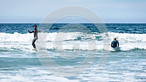 Young couple surfing with surfboard on waves in Atlantic ocean