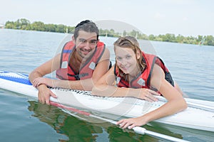 Young couple swiming with paddle board in lake