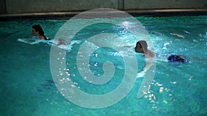 young couple swimming in pool with waterfall and underwater lights