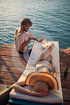 A young couple in swimsuit having a good while sunbathing on the river bank. Summer, river, vacation