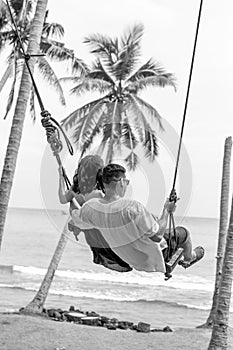 Young couple swinging on the tropical beach of Bali island, Indonesia.