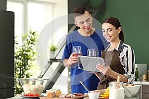 Young couple with tablet reading PC recipes in kitchen