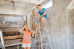 young couple take a break after tiredly fixing the ceiling photo