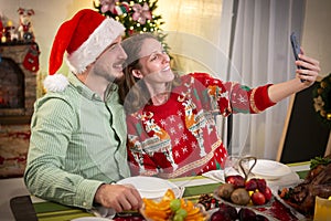 Young couple taking a selfie at a Christmas party at home