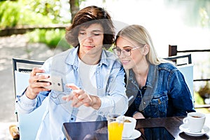 Young couple taking selfie while drinking coffee at cafe`s garde
