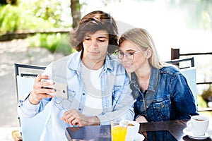 Young couple taking selfie while drinking coffee at cafe`s garde