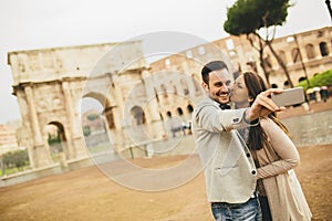 Young couple taking selfie in front of Colosseum in Rome, Italy