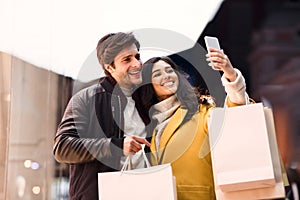 Young couple taking selfie after shopping in city mall