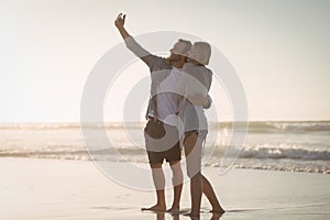 Young couple taking selfie on shore at beach