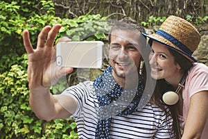 Young couple taking selfie with smart phone camera in outdoors.