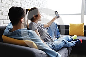 Young Couple Taking Selfie On Sofa At Home