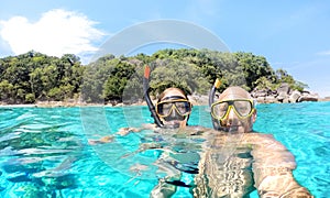 Young couple taking selfie in tropical scenario with waterproof camera - Boat trip snorkeling excursion at Similan islands