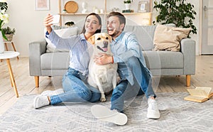 Young couple taking selfportrait with dog at home
