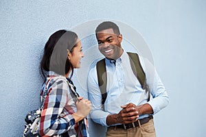 Young couple talk leaning against a grey wall