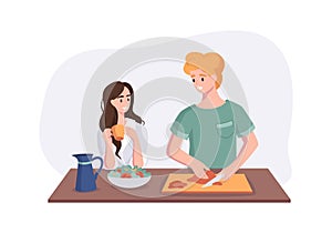 Young couple is talking while cooking breakfast at the dinner table in the kitchen. Woman drinking coffee and talking to