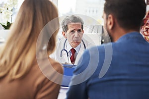 Young couple talking with gynecologist in doctorÃ¢â¬â¢s office photo