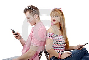 Young couple talking on mobile phones sitting back to back.