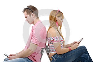 Young couple talking on mobile phones sitting back to back.