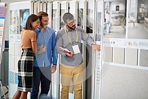 Young couple talking with salesman abut interior decor at ceramic tiles store