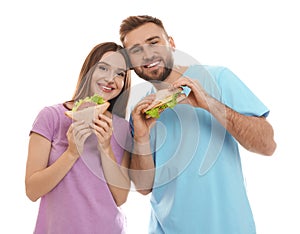 Young couple with tasty sandwiches on background