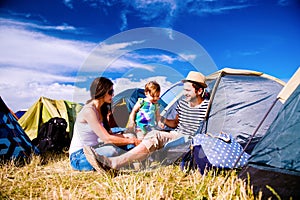 Young couple with their baby daughter in tent, summer