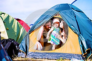 Young couple with their baby daughter in tent, summer