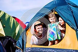 Young couple with their baby daughter in tent, summer