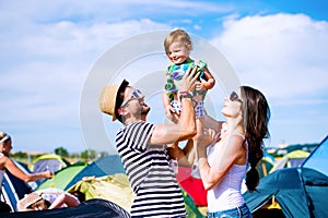 Young couple with their baby daughter between tents, summer