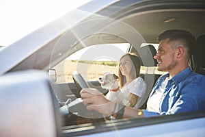 Young couple and their dog traveling by car in summertime