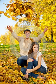 Young couple throwing autumn leaves