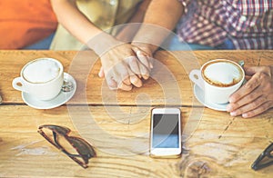 Young couple toasting coffee cappuccino at bar cafeteria shop - People holding each othres hands for tender love moments -