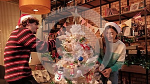 Young couple together decorating Christmas tree in the living room.