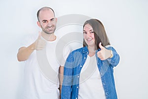 Young couple together over white isolated background doing happy thumbs up gesture with hand