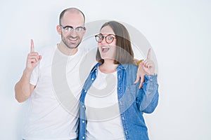 Young couple together wearing glasses over white isolated background surprised with an idea or question pointing finger with happy