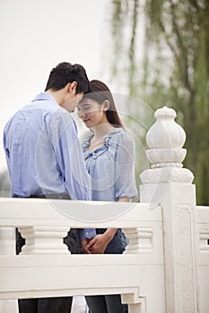 Young Couple Touching Foreheads and Holding Hands on a bridge