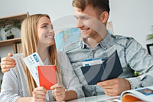 Young couple in a tour agency travelling concept holding documents looking on each other
