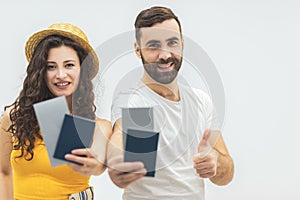 Young couple in a tour agency travelling holding documents and keeping thumbs up.