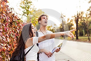 Young couple of tourists consulting a city guide and the digital tablet gps in the street searching locations