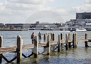 Young couple tourists looking and pointing to Rotterdam city harbour, future architecture concept, industrial lifestyle