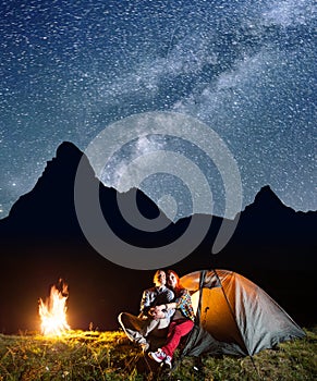 Young couple tourists looking to the shines starry sky and Milky way in the camping at night near campfire