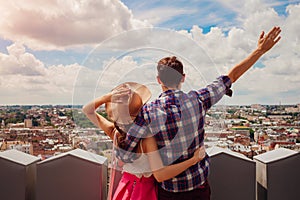 Young couple of tourists with raised hands looking on Lviv, Ukraine from viewpoint