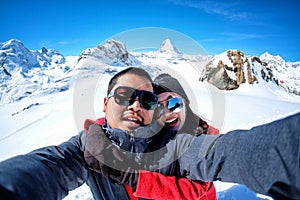 Young Couple Tourists selfie with mobile phone near view of snow mountain Matterhorn, Zermatt, Switzerland