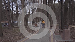 Young couple of tourists walking along the path in the park with backpacks on their backs. The man leads the bicycle and